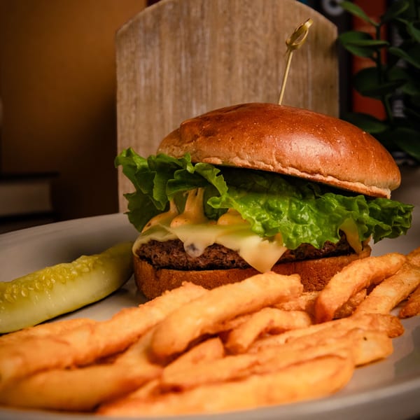 A cheeseburger with lettuce and special sauce, served with golden fries and a pickle spear.