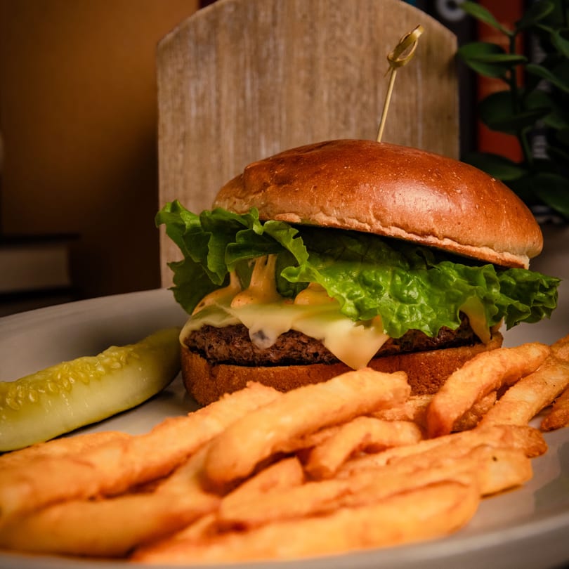 A cheeseburger with lettuce and special sauce, served with golden fries and a pickle spear.